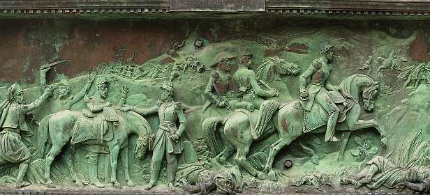 28: 10 05 05_0159_AP13<br>Relief op de voet van het standbeeld tussen de kerk en het stadhuis