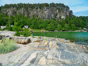 De gneisses op de voorgrond hebben een verticale structuur en zijn ca. 1500 miljoen jaar oud. De kalksteen en leisteen in de steile rand op de achtergrond zijn horizontaal en zijn "slechts" ca. 500 miljoen jaar oud. Voor meer info, zie  www.geoparken.no