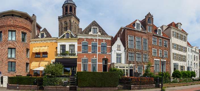 De toren van de Grote Kerk tussen huizen langs de IJssel
